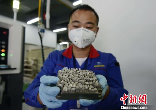 華曙高科的工作人員展示剛剛用3D打印出來的義齒金屬基底。　楊華峰 攝